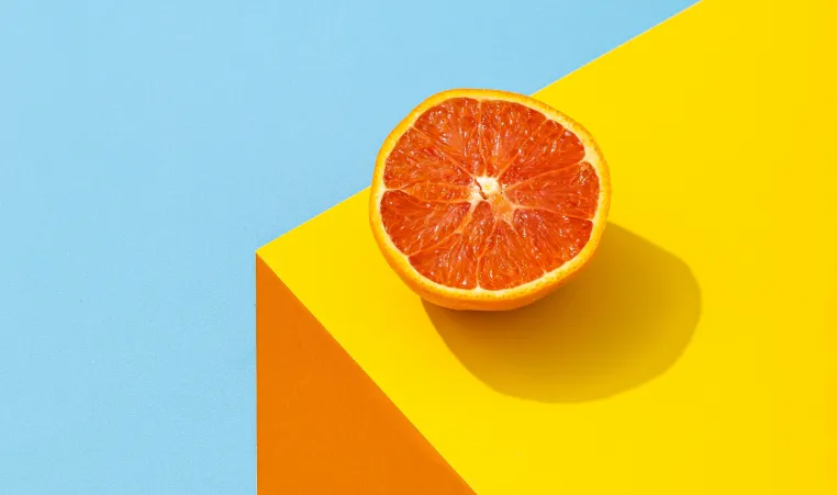 Orange sitting on an orange table with a light blue background