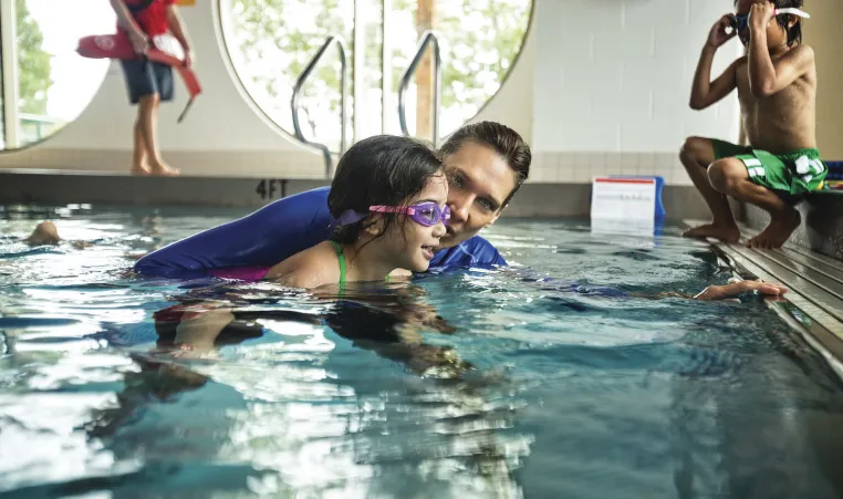 A child learning to swim at a YMCA pool