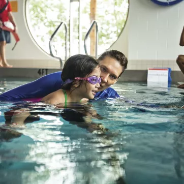 A child learning to swim at a YMCA pool